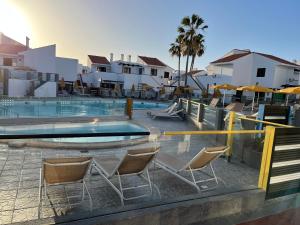 a swimming pool with two chairs and a swimming pool at Poema de Liria in Caleta De Fuste