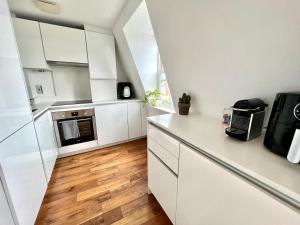 a kitchen with white cabinets and a wooden floor at The Loft Queens Park in London