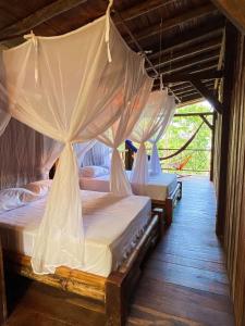 3 camas en una habitación con mosquiteras en La Martina Ecolodge, en Nuquí