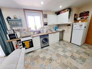 cocina con electrodomésticos blancos y suelo de baldosa. en Casa de los Suenos Granada, 