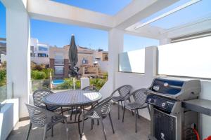 un patio con mesa, sillas y parrilla en Villa Premium Los Mangos Casasol en Nerja
