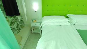 2 Betten in einem kleinen Zimmer mit grüner Wand in der Unterkunft Hotel Casa Nicola in Ischia