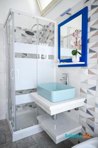 ein Badezimmer mit einem blauen Waschbecken und einer Glasdusche in der Unterkunft Appartamenti Jolly by SalentoGo in Torre Lapillo