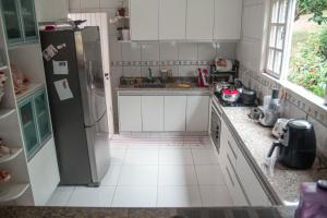 a kitchen with white cabinets and a refrigerator at Vale das Maritacas Teresópolis in Teresópolis