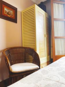um quarto com uma cama, uma cadeira e uma janela em La Llosa de Sámano em Castro-Urdiales