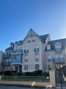 a large white building with blue balconies at Proche St-Malo, plages, appart 50m2 avec jardin in Dinard