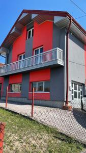 een rood en grijs gebouw met een hek ervoor bij Cazin Centar Ćuprija in Cazin