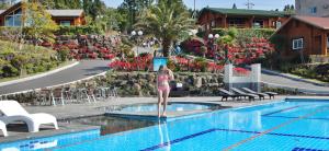 a woman in a bikini standing next to a swimming pool at Jeju I've Hotel & Resort in Seogwipo