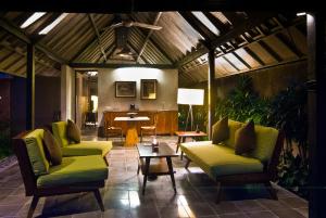 a living room with green chairs and a table at Komea Villa in Canggu