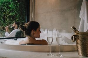 une femme assise dans une baignoire avec deux verres à vin dans l'établissement LaPianta, à Monte Verde