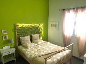 a bedroom with a bed with green walls and a window at Un Paraiso En Tenerife in Punta del Hidalgo