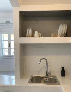 a kitchen sink with plates and cups on a shelf at Juli’s Suites in Mérikhas