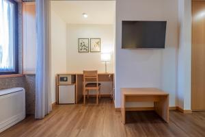 a hotel room with a desk and a table and a television at Casa de Fervença in Barcelos