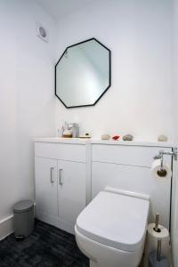 a bathroom with a white toilet and a mirror at Incredible summer winter 32c heated pool hot tub bar in Kent