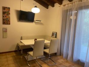 une salle à manger avec une table, des chaises et une télévision dans l'établissement Casa Conchiglia - Aprilia Marittima - Corte Grande, à Aprilia Marittima