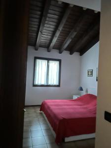 a bedroom with a red bed and a window at Casa Conchiglia - Aprilia Marittima - Corte Grande in Aprilia Marittima