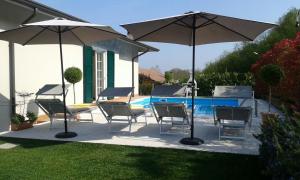 un patio con sillas y sombrillas junto a una piscina en Villa Elisa Relax, en Pozzolengo