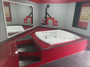 Baño de azulejos rojos con bañera y espejo en La Selva Auto Hotel ADULTS ONLY en Soncuantla