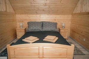 a bed in a wooden cabin with two towels on it at Górskie Chatki Krysi i Piotrka Perłowy in Stronie Śląskie
