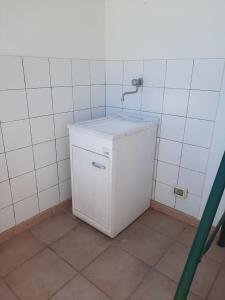 Un pequeño refrigerador blanco en una habitación con azulejos blancos. en casa sonia, en Torre Saracena