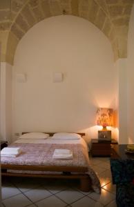 1 dormitorio con 1 cama y 1 mesa con lámpara en La Cecia - Casa vacanze nella campagna salentina, en Cavallino di Lecce