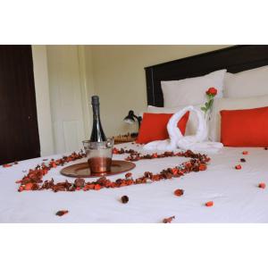 Una cama con una botella de champán y un cisne y rosas. en Boikhutsong Bed & Breakfast, en Maseru