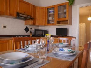 una cucina con tavolo in legno, piatti e bicchieri di Domus Tilla a Piombino