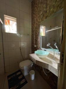 a bathroom with a sink and a toilet and a mirror at Chácara recanto Feliz in Pirenópolis