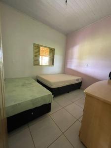 two beds in a small room with a window at Chácara recanto Feliz in Pirenópolis