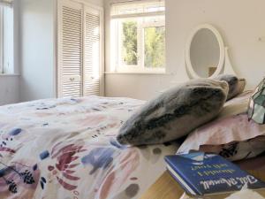 1 dormitorio con cama con almohadas y libro en Wildwood Cottage en Germansweek