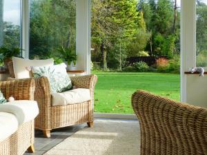 a porch with wicker chairs and a view of a yard at Wildwood Cottage in Germansweek