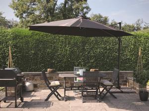 a table and chairs under an umbrella next to a grill at Wildwood Cottage in Germansweek