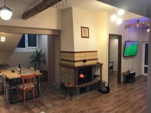a living room with a fireplace and a table and a television at Mansard underneath the stars in Pripek