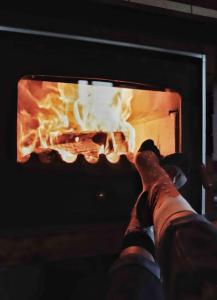 a person with their feet up in front of a fireplace at Mansard underneath the stars 