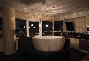 a bath tub in a room with a view of a city at sky FLAT jacuzzi sauna 27 FLOOR in Klaipėda