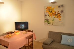 a living room with a table and a tv at Appartamento Genziana in Santa Maria Navarrese
