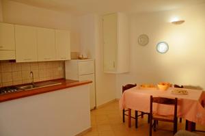 a kitchen with a table and a sink and a clock on the wall at Appartamento Genziana in Santa Maria Navarrese