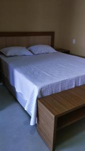 a bedroom with a bed with a white bedspread and a wooden frame at Hotel do Carmo in Piracuruca
