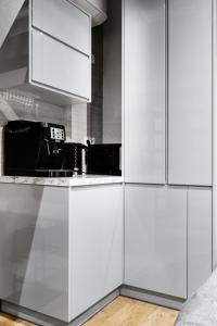 a white kitchen with white cabinets and a microwave at HOUSEHOST Apartment:Bracka 3/15B in Krakow