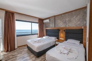 two beds in a hotel room with a view of the ocean at Hotel Sunday Beach in Kusadası