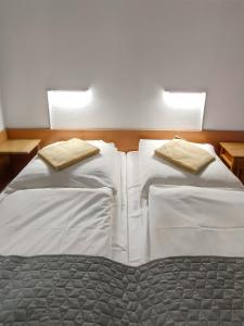 2 camas en un dormitorio con sábanas y almohadas blancas en Villa Park Maikuhle, en Kołobrzeg