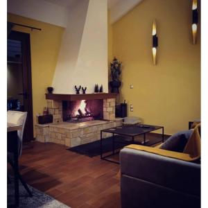 a living room with a fireplace with a couch and a table at REST SUITE On The Pedestrian Street in Kalavrita