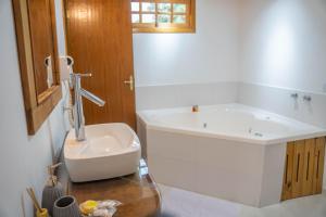 a bathroom with a tub and a toilet and a sink at Hotel Ascona in Campos do Jordão