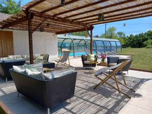 a patio with chairs and tables and a wooden pergola at Les Galapons in Trept