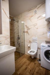 a bathroom with a toilet and a sink and a washing machine at Apartment Leona in Kraljevo