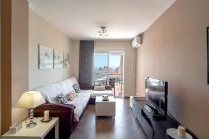 ein Wohnzimmer mit einem Sofa und einem TV in der Unterkunft Almijara Apartments Casasol in Nerja