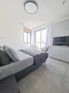 a bedroom with a large bed and a large window at חוויה בכיכר in Netanya