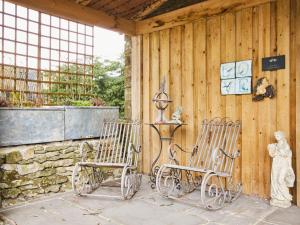 2 fauteuils à bascule assis à côté d'un mur en pierre dans l'établissement Love Nest, à Bakewell
