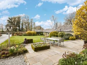 a patio with a table and benches in a garden at The Farmhouse in Bakewell