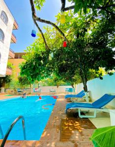 a swimming pool with blue lounge chairs and a tree at Kafkas Hotel in Antalya